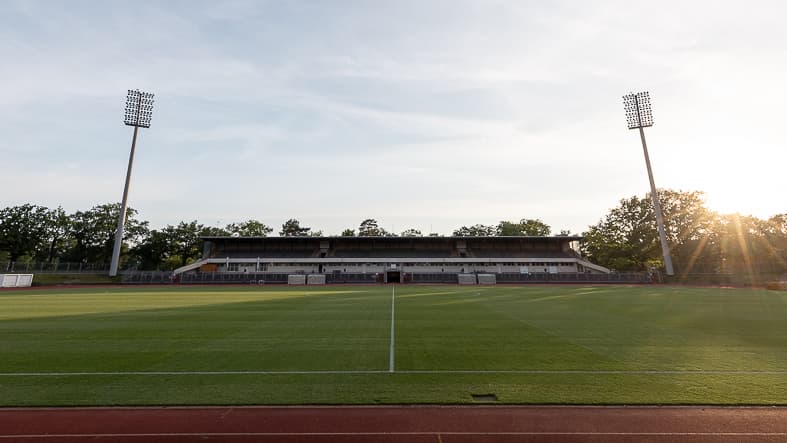 Die Haupttribüne und die Flutlichtmasten des Mommsenstadions im Abendlicht.